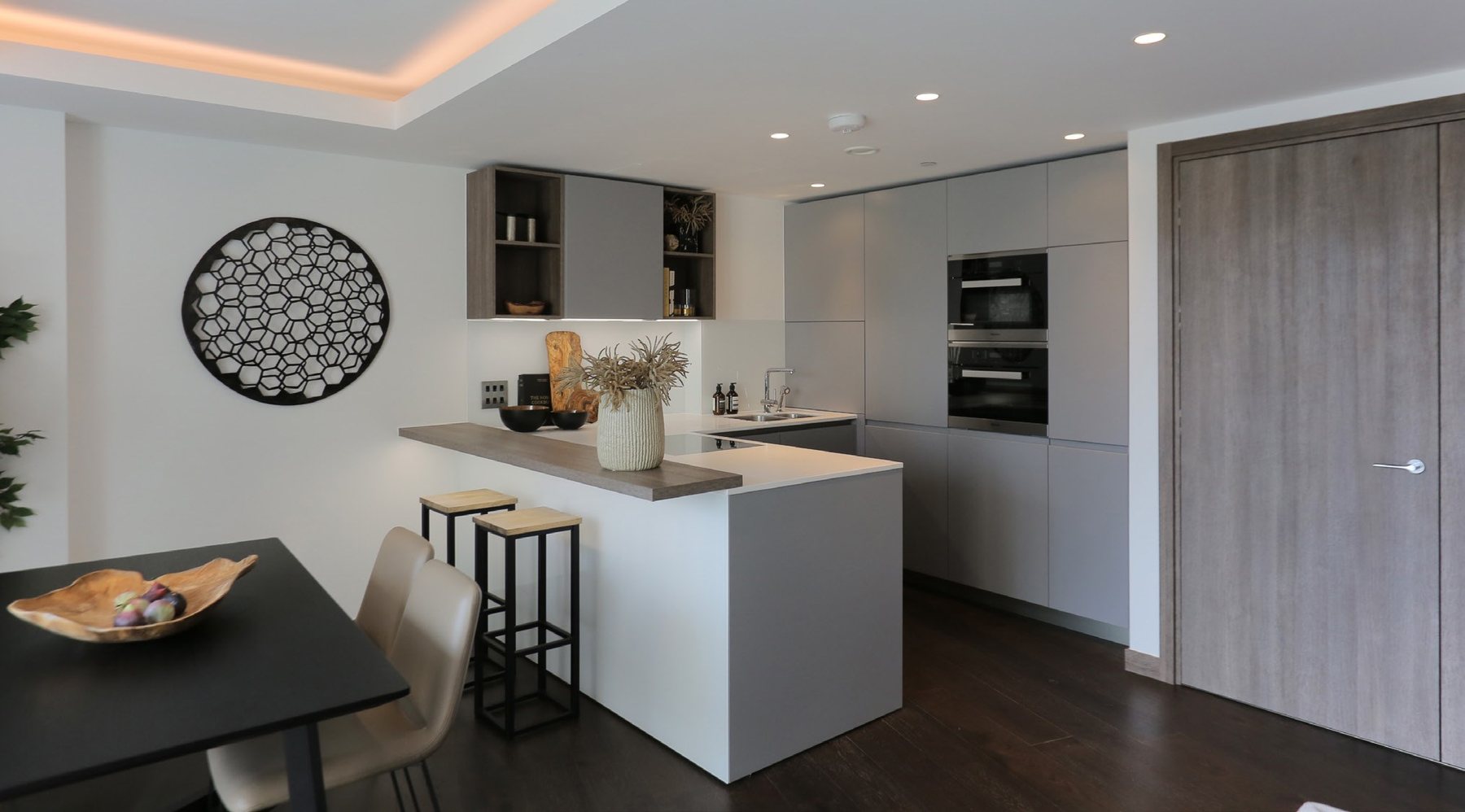 Bright apartment kitchen with a white island, stools and integrated ovens