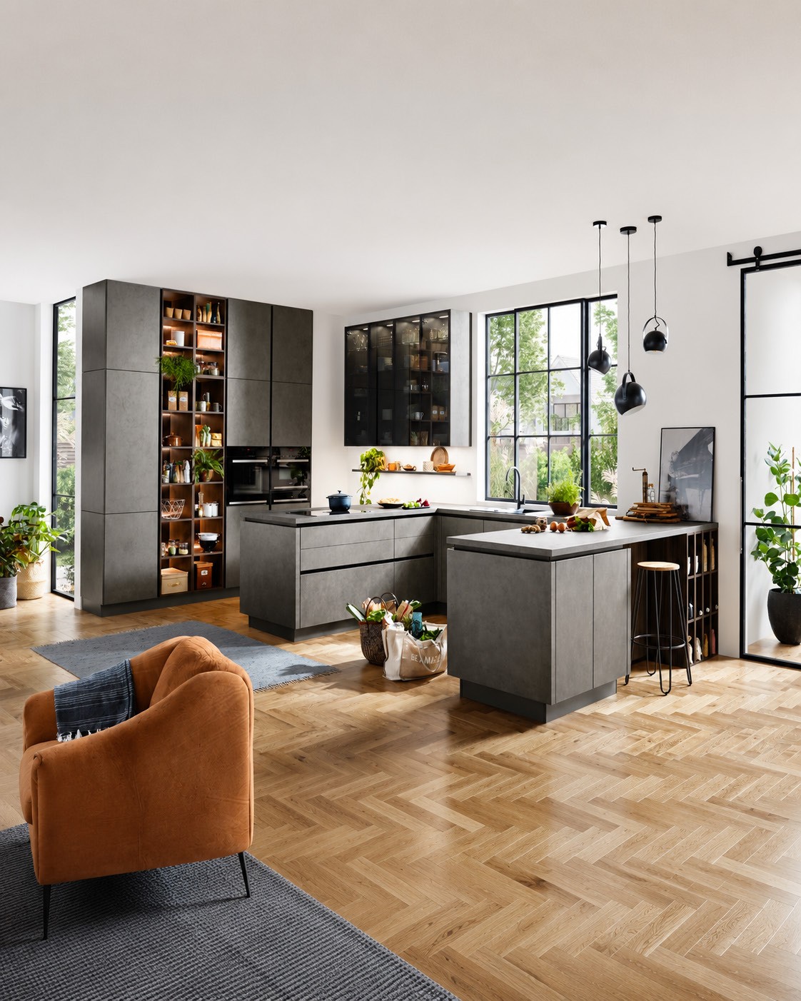 Open-plan dark stone kitchen with glazed cabinets, a dining peninsula and herringbone oak floor